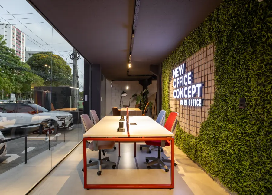 Sala de trabalho com parede verde e mesa colaborativa.